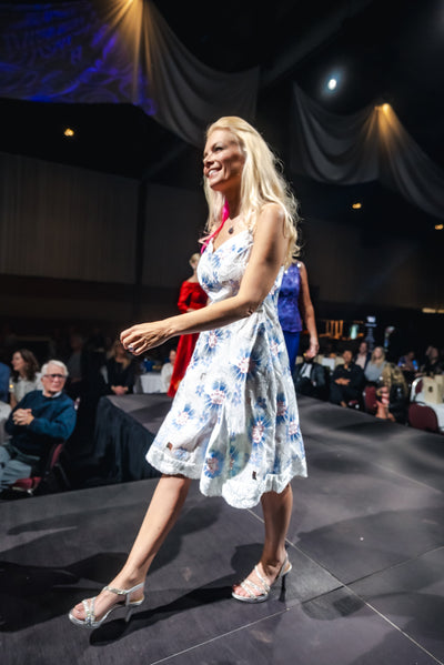 Woman in a floral dress on a stage with a dark background